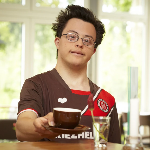 Servicekraft des Robben Cafés serviert eine Tasse Kaffee