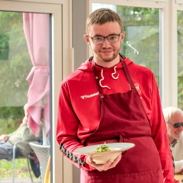 Servicekraft des Robben Cafés mit einem frisch angerichteten Gericht